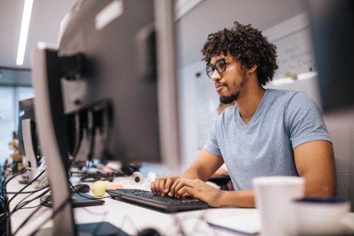 desenvolvedor mobile: homem jovem trabalhando em escritório iluminado em frente ao computador