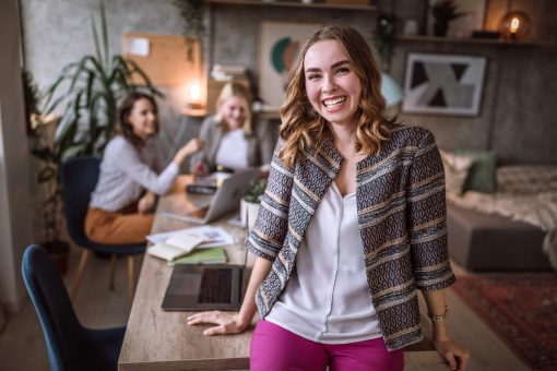 como ser um empreendedor: jovem mulher sorrindo em ambiente de escritório descontraído